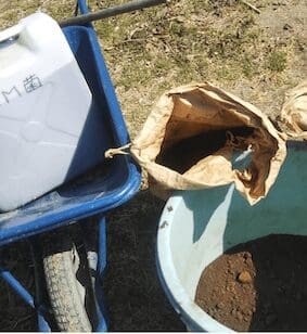 堆肥作りのため、一輪車に乗せられたEM菌の容器とコーヒーかす。他の材料と混ぜる前の準備風景。