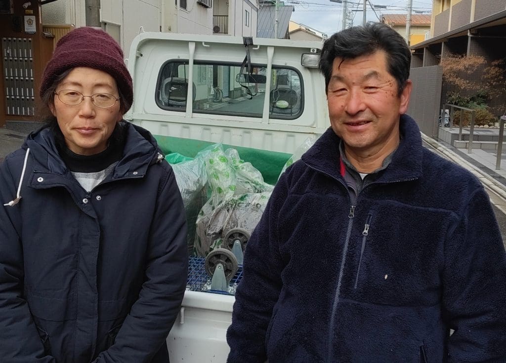 コーヒーかすの袋を満載した軽トラックの前に立つ、京都・伏見「船越農園」のご夫妻