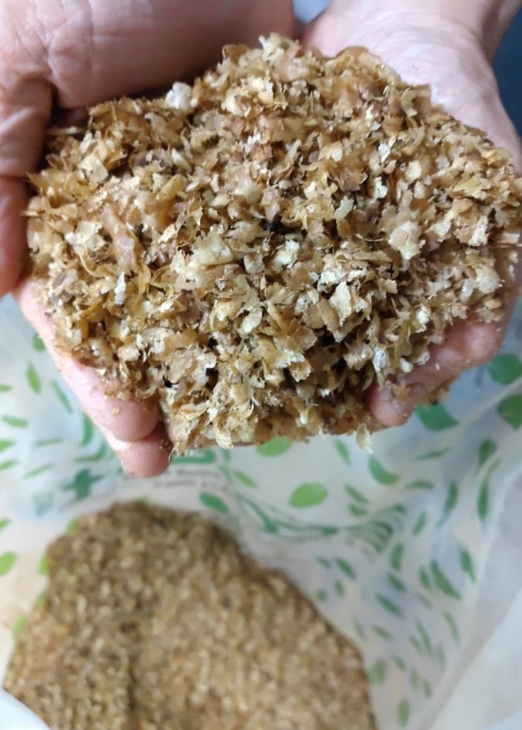 両手で包み込むように持たれた、ふわふわとしたコーヒーチャフ（シルバースキン）のアップ写真。